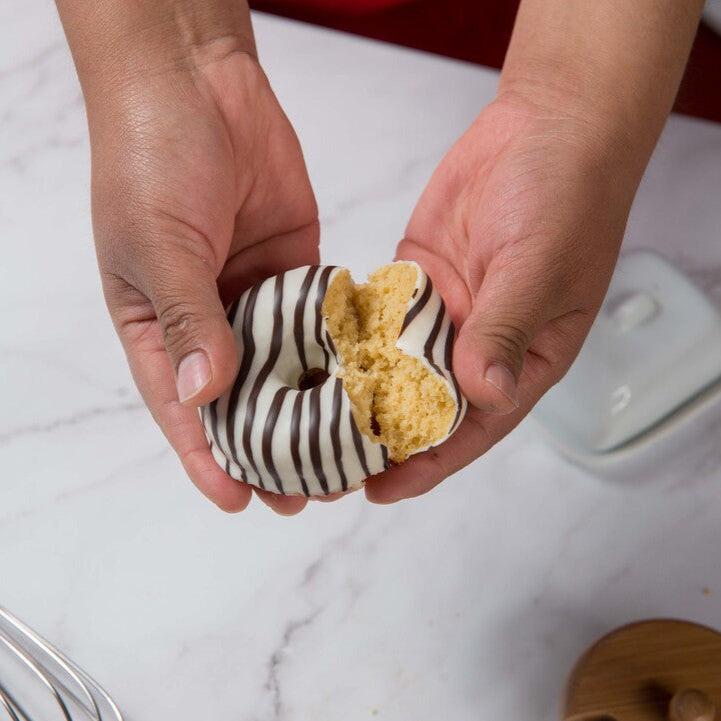 Person holding a half-eaten FITbelly donut with a marble countertop in the background