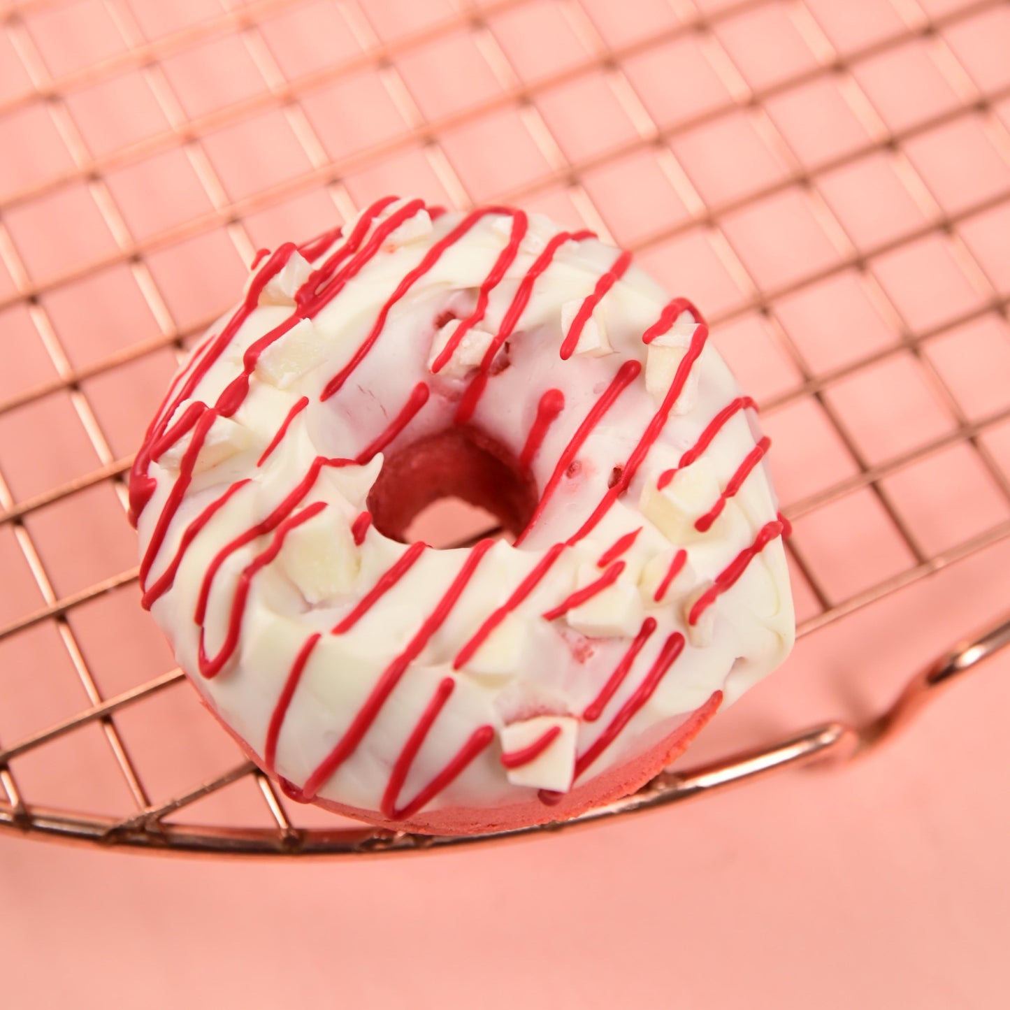 FITbelly donut with white glaze and red drizzle on a pink background