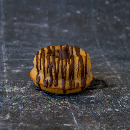 FITbelly keto donut with chocolate drizzle on a textured dark surface