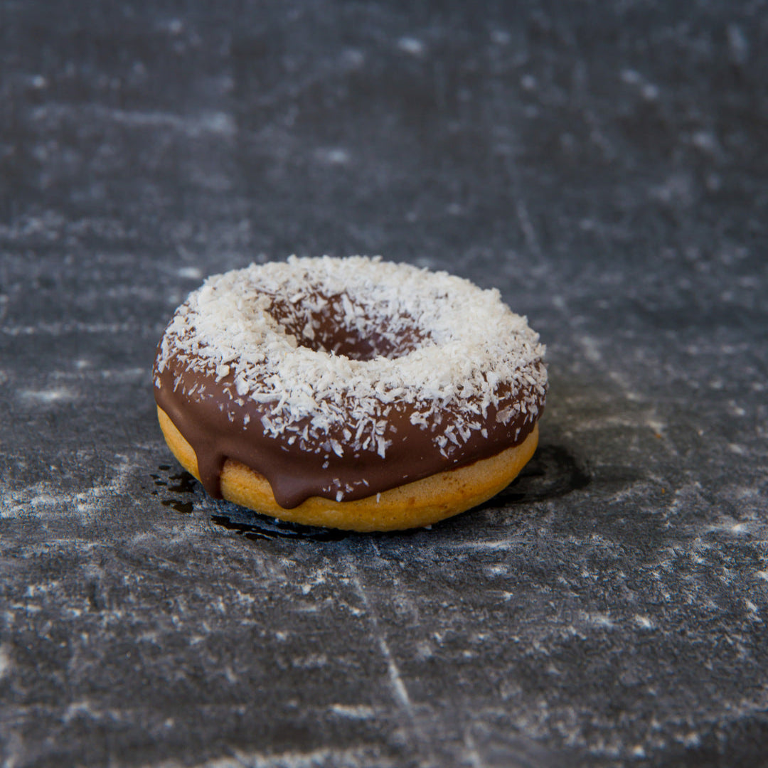 FITbelly donut with chocolate glaze and white powder on a textured dark surface