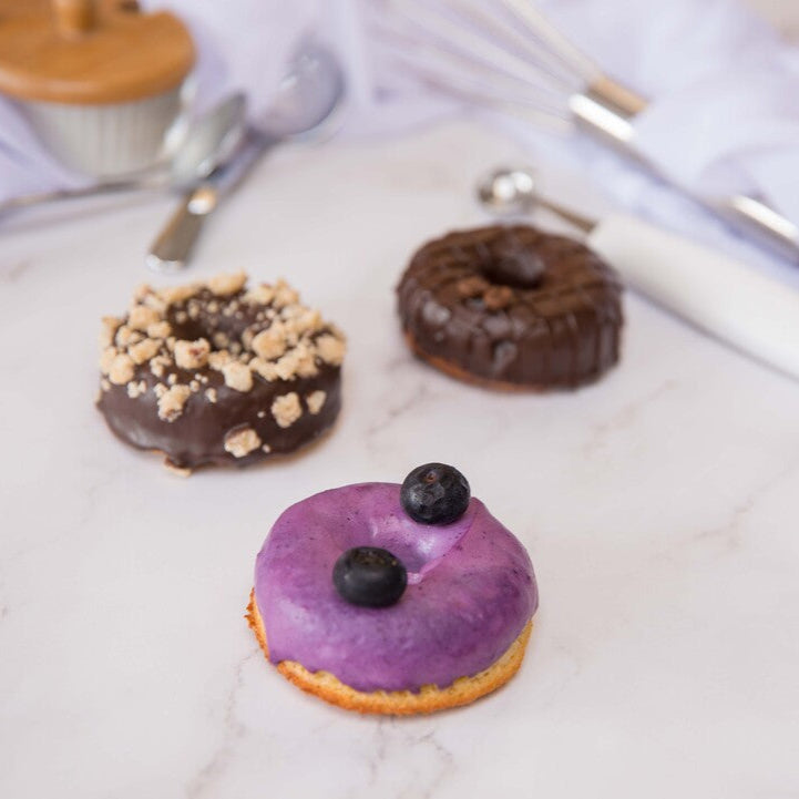 Three FITbelly donuts with different toppings on a marble surface